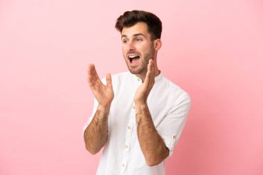 Pembe arka planda yalıtılmış beyaz, yakışıklı, şaşırtıcı bir yüz ifadesi olan genç adam.