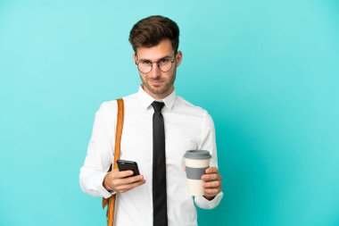 İş adamı izole edilmiş arka planda kahve ve cep telefonu tutuyor.