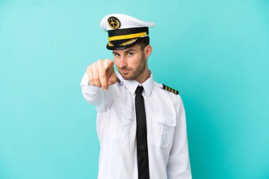 Kafkasyalı uçak pilotu mavi arka planda izole edilmiş. Parmağını kendine güvenen bir ifadeyle işaret ediyor.