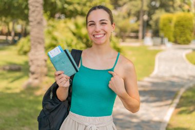 Dışarıda elinde pasaport tutan genç ve güzel bir kadın. Sürpriz bir yüz ifadesi.