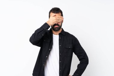 İzole edilmiş beyaz arka planda sakallı genç bir adam gözlerini elleriyle kapatıyor. Bir şey görmek istemiyorum.