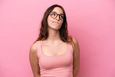 Genç beyaz kadın pembe arka planda izole edilmiş ve yukarı bakıyor.