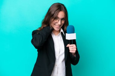 Genç TV sunucusu kadın mavi arka planda izole edilmiş gülüyor.