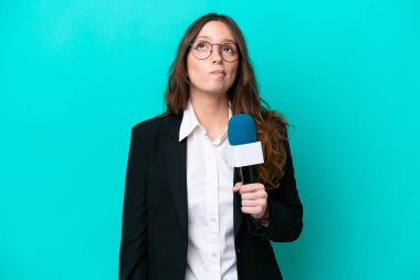 Genç TV sunucusu kadın mavi arka planda izole edilmiş ve yukarı bakıyor