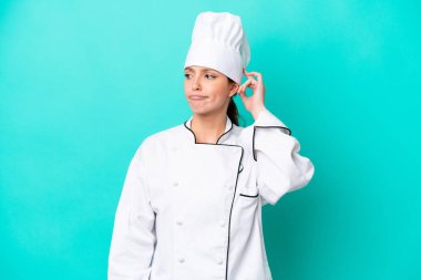 Kafkasyalı genç aşçı kadın mavi arka planda izole edilmiş. Şüpheleri var ve kafası karışmış bir yüz ifadesi var.