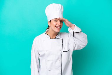 Kafkasyalı genç bir aşçı kadın mavi arka planda izole edilmiş. Bir şeye bakmak için uzaklara bakıyor.
