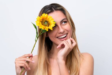 Beyaz arka planda izole edilmiş beyaz tenli genç bir kadın gülümserken elinde bir ayçiçeği tutuyor. Portreyi kapat