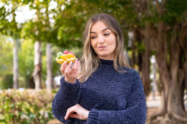 Genç, güzel Romen kadın, elinde üzgün bir ifadeyle açık havada bir tart tutuyor.