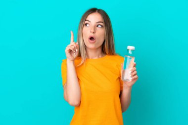 Mavi arka planda izole edilmiş bir şişe suyu olan genç Romen kadın, bir fikrin parmağı yukarı kaldıracağını düşünüyor