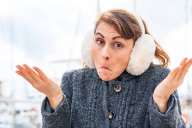 Esmer kadın, açık havada kışlık kuklalar takıp kuşkulu hareketler yapıyor.