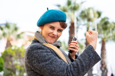 Dışarıdaki esmer kadın cep telefonu kullanıyor ve arkasını işaret ediyor.