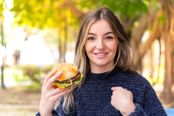 Młoda Ładna Rumuńska Kobieta Trzyma Hamburgera Świeżym Powietrzu Zaskakującym Wyrazem — Zdjęcie stockowe