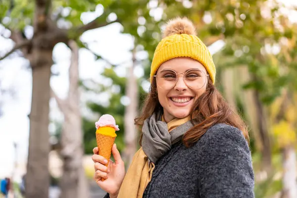 Brunette woman with a cornet ice cream at outdoors smiling a lot