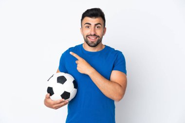 Yakışıklı genç futbolcu yalıtılmış duvarın üzerinden bir ürün sunmak için kenarı işaret ediyor.