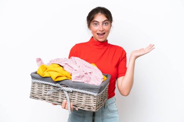 Beyaz arka planda yüzü şoke olmuş beyaz bir elbise sepeti tutan beyaz bir kadın.