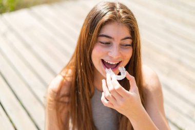 Görünmez diş telleri tutan beyaz bir kadın.