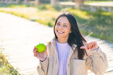 Açık havada elmalı genç bir kadın gururlu ve kendini beğenmiş.