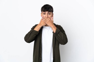 İzole edilmiş beyaz arka planı olan genç bir adam elleriyle ağzını kapatıyor.