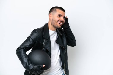 Beyaz arka planda izole edilmiş motosiklet kasklı genç beyaz bir adam elini kulağına koyarak bir şeyler dinliyor.