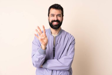 Sakallı beyaz bir adam soyutlanmış arka planda ceket giyiyor mutlu ve parmakları olan dört kişi sayıyor.
