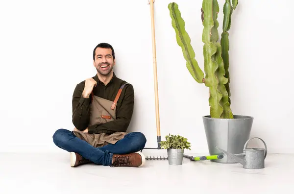 Gardener man sitting on the floor at indoors laughing