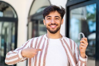 Yakışıklı bir Arap 'ın görünmeyen diş tellerini açık havada tutması şaşırtıcı bir yüz ifadesi.