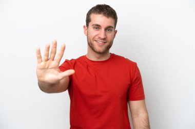 Beyaz arka planda izole edilmiş genç beyaz adam parmaklarıyla beşi sayıyor.