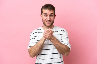 Pembe arka planda izole edilmiş genç beyaz adam gülüyor.