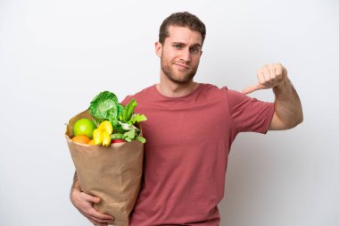 Beyaz arka planda izole edilmiş bir alışveriş çantası tutan beyaz bir adam gururlu ve kendini beğenmiş.