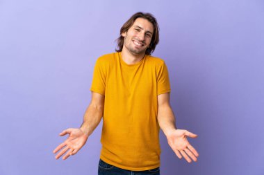 Mor arka planda izole edilmiş genç yakışıklı adam mutlu ve gülümsüyor.