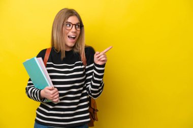 Young student woman isolated on yellow background background intending to realizes the solution while lifting a finger up