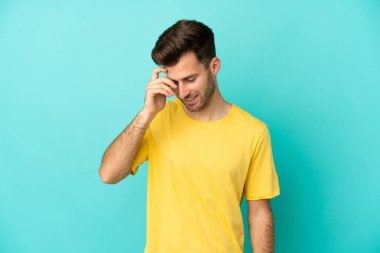 Genç beyaz yakışıklı adam mavi arka planda izole edilmiş gülüyor.