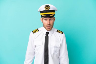 Kafkasyalı uçak pilotu mavi arka planda şaşırmış bir yüz ifadesiyle izole edildi.
