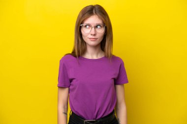 Sarı arka planda izole edilmiş genç bir İngiliz kadın şüpheli hareketler yapıyor.