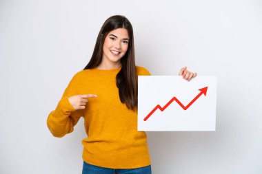 Beyaz arka planda izole edilmiş genç Brezilyalı kadın elinde büyüyen bir istatistik oku sembolü olan bir tabela tutuyor ve onu işaret ediyor.