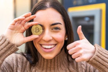 Dışarıda Bitcoin tutan genç bir kadın.