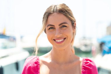 Açık havada genç sarışın bir kadın Neşeli bir ifadeyle