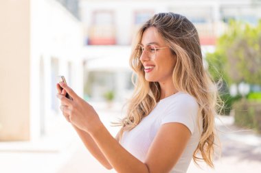 Güzel sarışın Uruguaylı kadın cep telefonuyla mesaj ya da e-posta gönderiyor.