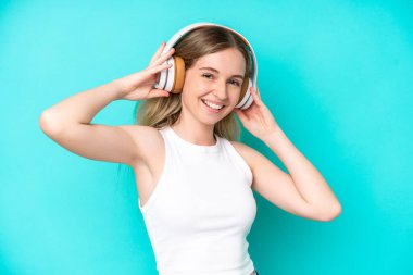 Blonde English young girl isolated on blue background listening music