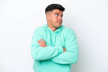 Beyaz arka plandaki beyaz tenli yakışıklı adam omuzlarını kaldırırken şüpheyle hareket ediyor.