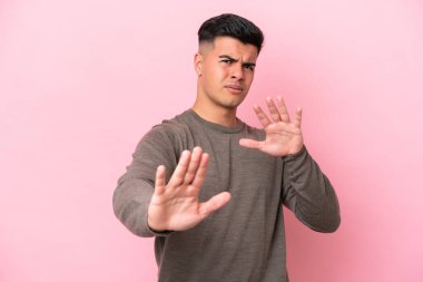 Beyaz tenli yakışıklı adam pembe arka planda izole edilmiş gergin eller öne doğru uzanıyor.