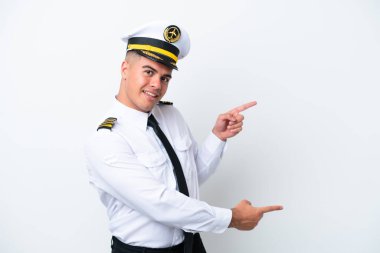 Uçak pilotu beyaz arka planda izole edilmiş beyaz bir beyaz adam parmak göstererek bir ürün sunuyor.