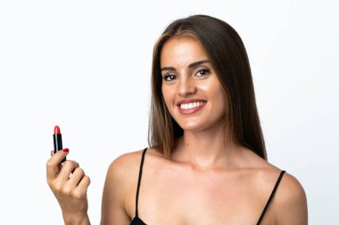 Genç Uruguaylı kadın beyaz arka planda izole edilmiş kırmızı ruj tutuyor.