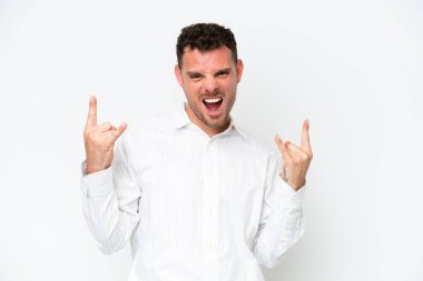 Young caucasian handsome man isolated on white background making horn gesture