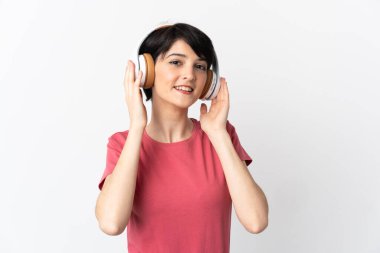 Kısa saçlı bir kadın beyaz arka planda müzik dinliyor.