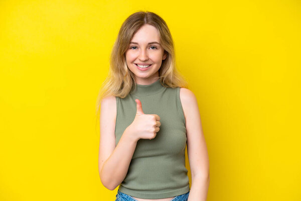 Blonde English young girl isolated on yellow background giving a thumbs up gesture