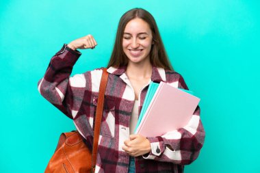 Mavi arka planda izole edilmiş genç beyaz kadın güçlü bir jest yapıyor.