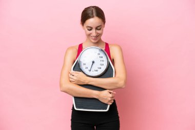 Pembe arka planda tartı makinesiyle izole edilmiş beyaz bir kadın.