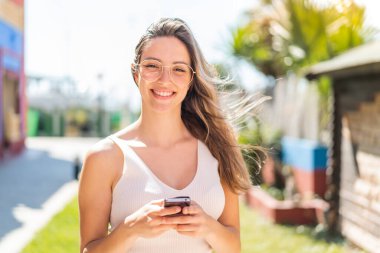 Dışarıdaki güzel bayan cep telefonuyla mesaj yolluyor.