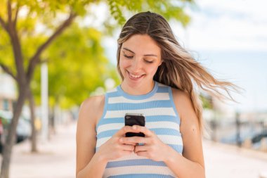 Dışarıdaki güzel bayan cep telefonuyla mesaj ya da e-posta yolluyor.